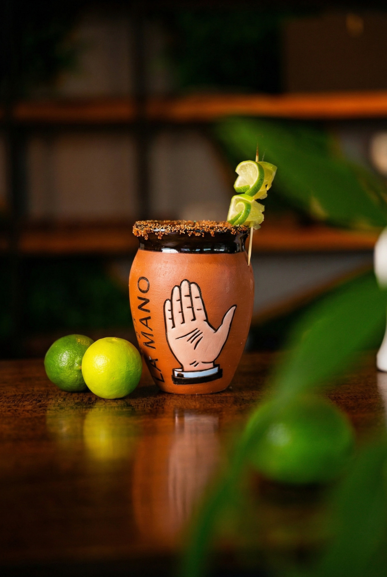 A house margarita served in a terracotta cup with chili salt rim and lime garnish